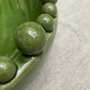 Large green ceramic bowl with balls on rim