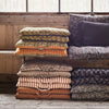 Stack of patterned cushions on a wooden bench with a window in the background